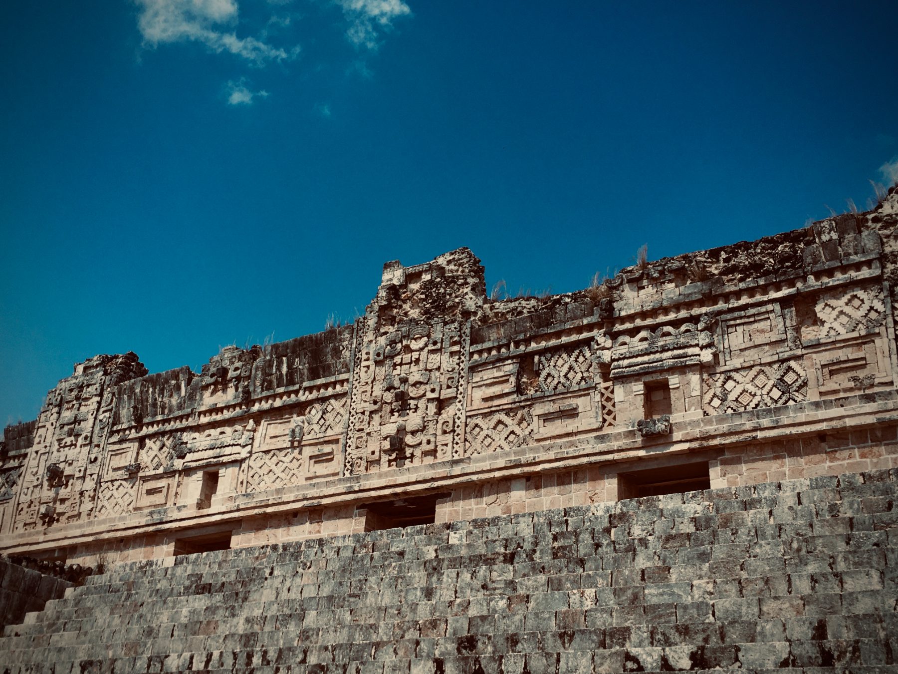 A Maya pyramid wall with a column of rain-god mask carvings